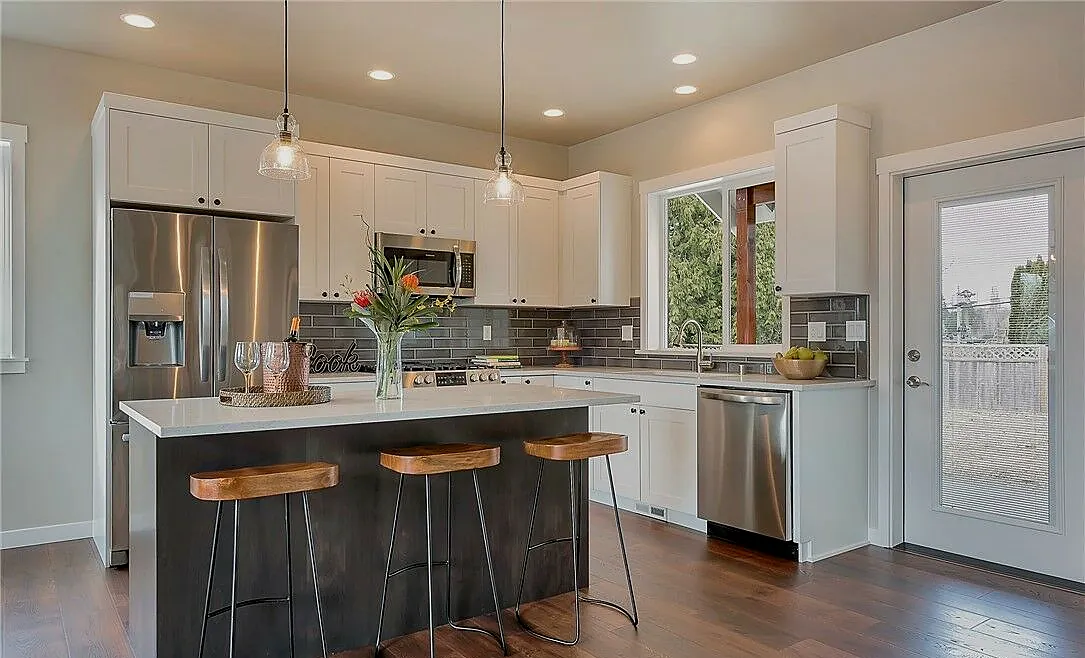 White kitchen with dark island and wood stools